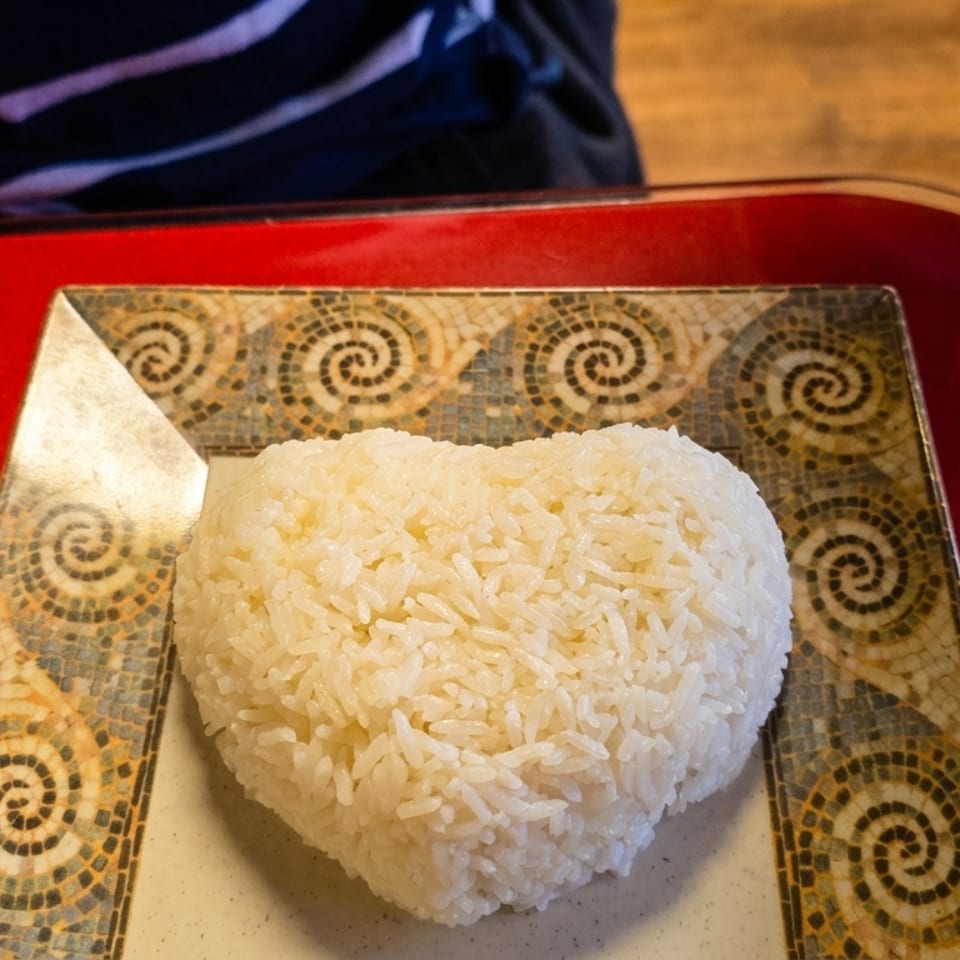Heart-shaped white rice on a decorative plate with a red placemat.