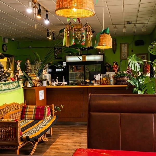 Vibrant green restaurant interior with ornate decor, wooden furniture, and lush plants.